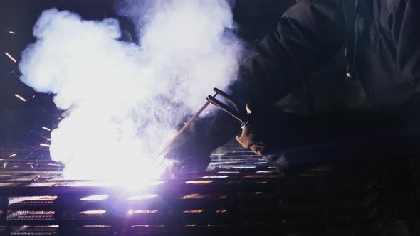 A Worker with a Welding Machine Performs Welding Work on Metal alt