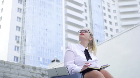 business woman makes entries in the diary while sitting on the steps