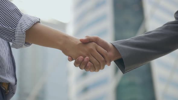 Asian businessmen shaking hands with partners have success while standing in the urban city.