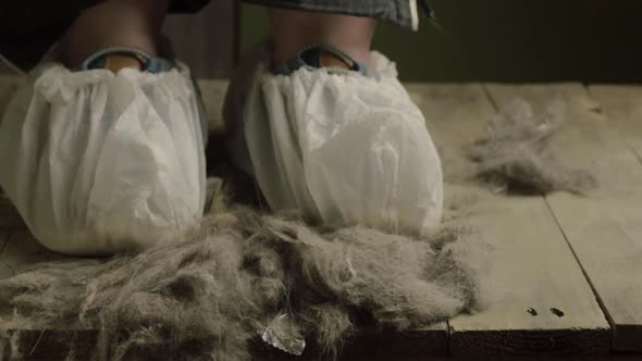 Pair of feet wearing disposable shoe protectors in dusty dirty environment alt