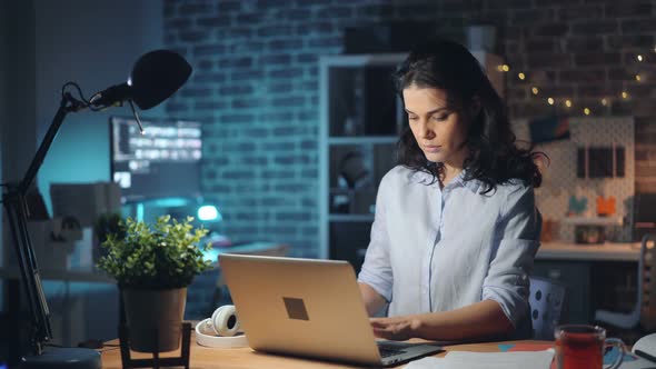 Girl Leaving Workplace at Night Turning Off Laptop and Lamp and Going Away alt