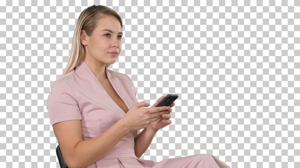 Smiling blonde woman sitting and using smartphone, Alpha Channel alt