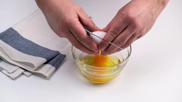 Breaking an egg into a glass bowl. Fresh organic egg falling into bowl.