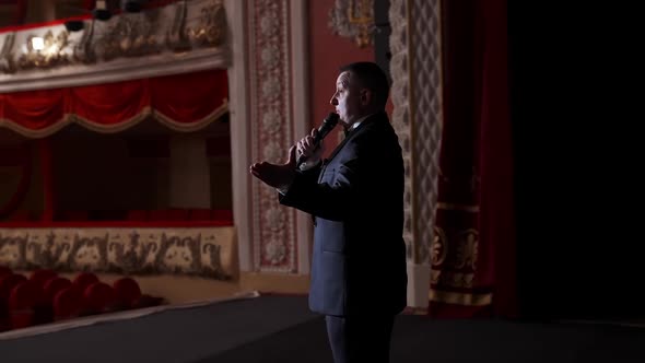 Presenter with microphone speaks with the empty auditorium.  alt