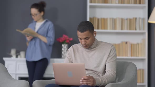 Young Handsome African American Man Opening Laptop Checking Email with Blurred Caucasian Woman alt