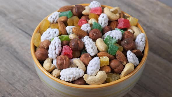 Sweets, raisin, candied fruit and nuts in a bowl rotating on a table. Close up view.