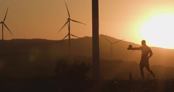 Athlete at Sunset Trains with a Kettlebell Lifting It Up. Silhouette Shooting. The Concept of alt