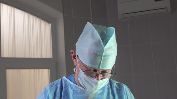 Closeup of a Surgeon During an Operation Looks at the Camera and Approvingly Nods alt