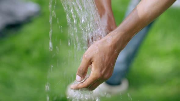 Closeup African American Male Hands Washing with Water Outdoors on Sunny Day alt