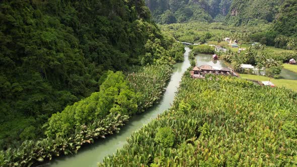 Aerial view of a river surrounded by jungle, mangroves, and limestone mountains. Filmed at a local v alt