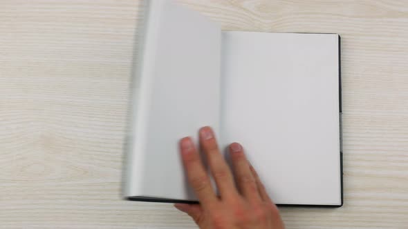 The Hand of a Businessman Puts and Opens an Empty Diary on the Table alt