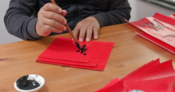 Man write chinese calligraphy for lunar new year alt