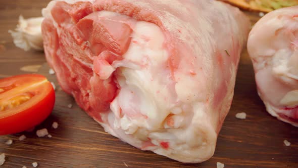 Two Raw Pork Drumsticks on Wooden Board Close Up alt