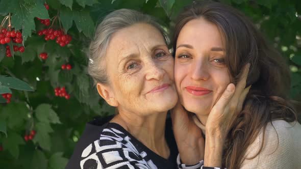 Happy Senior Mother in Eyeglasses is Hugging Her Adult Daughter the Women are Enjoying Together alt
