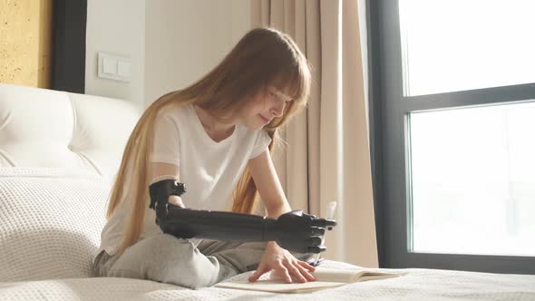 Disabled Girl Tries To Hold a Pen with an Artificial Arm. alt