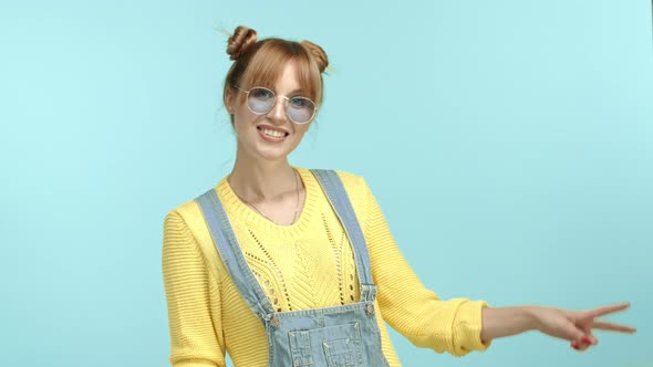 Glamour Young Woman in Stylish Sunglasses and Outfit Showing Peace Sign and Smiling Happy Having Fun