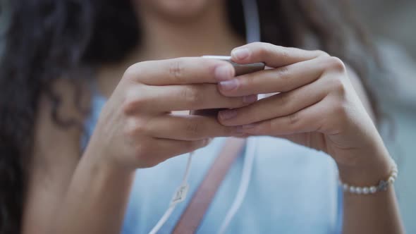 Closeup of Teenage Girl Holding Smartphone and Listening To Music alt