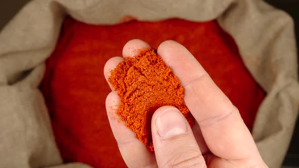 Human hand takes a pinch of red pepper powder from a sac