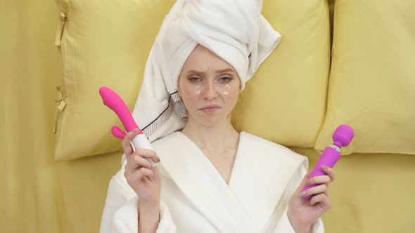 An Excited Young Woman Lies on the Bed and Chooses a Dildo a Sex Toy to Have Fun alt