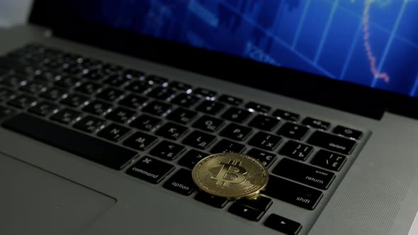 Dolly shot of Bitcoin BTC cryptocurrency. Golden coin on laptop keyboard, slow motion alt