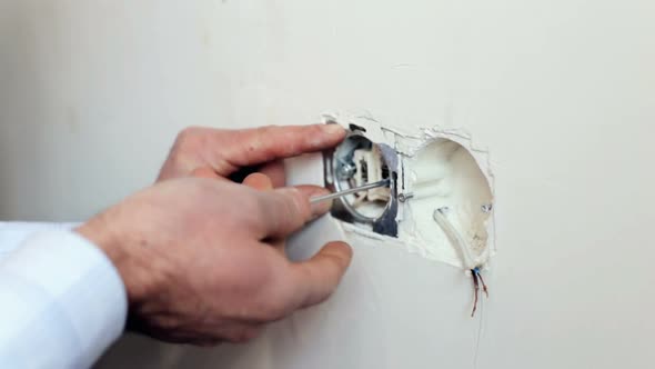 The electrician is installing the sockets in the apartment. alt