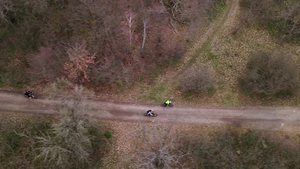 Aerial Top Down Shot of Young Sport Men Ride Bicycles on Countryside Road at Spring Cloudy Day alt