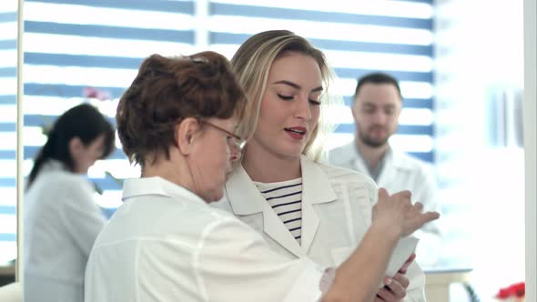Older Nurse Bringing Medical Document To Young Nurse and Male Doctor alt