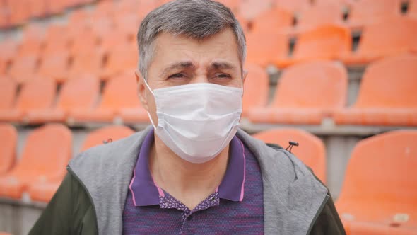 Closeup of the Face of a Fan in a Medical Mask at a Sports Stadium Actively Supporting His Team