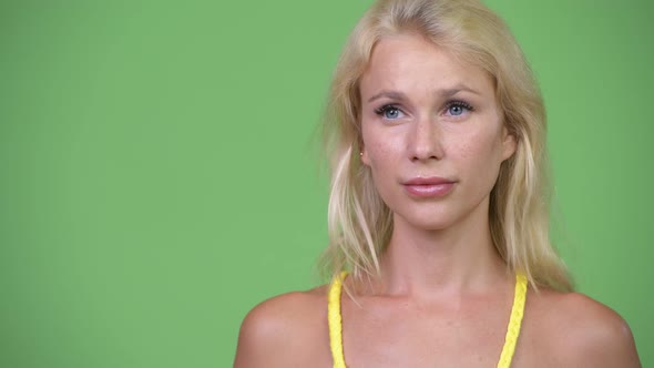 Young Happy Beautiful Blonde Woman Thinking Against Green Background