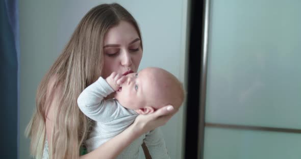 Happy Mother Holds Her Lovely Newborn Son Caresses Him and Rejoices in Room alt