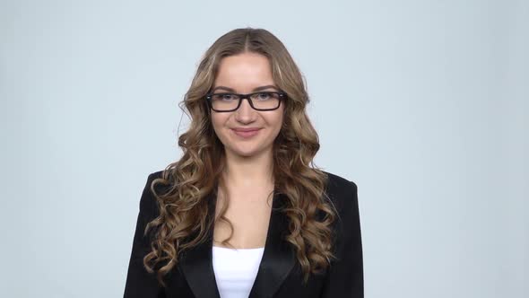 Girl Joyfully Shows House Keys on Gray Background in the Studio, Slow Motion alt