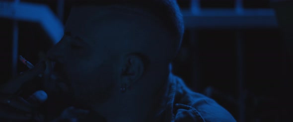 A man smoking a cigarette outside at night, dealing with anxiety and post trauma. alt