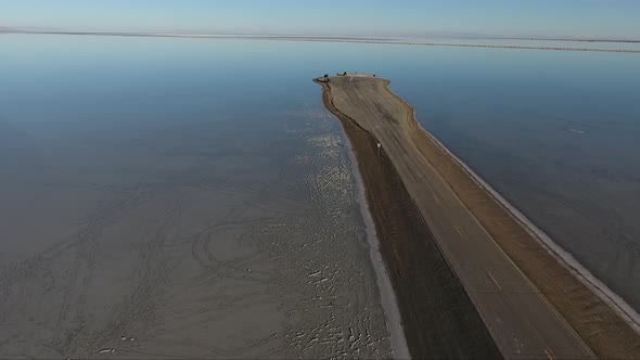 A drone shot flying over the Bonneville Salt Flats shows the Salt Flats causeway dividing the floode alt