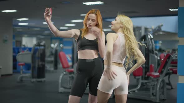 Young Slim Caucasian Millennial Women Taking Selfie in Gym Smiling and Posing alt