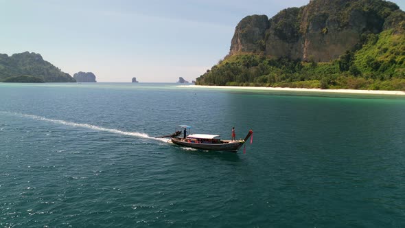 aerial drone tracking a tourist on a thai longtail boat motoring through the many islands of the and alt