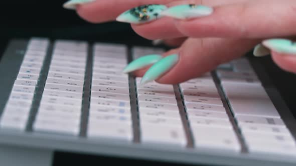 Business Woman's Fingers are Typing on the Keyboard of a White Laptop alt