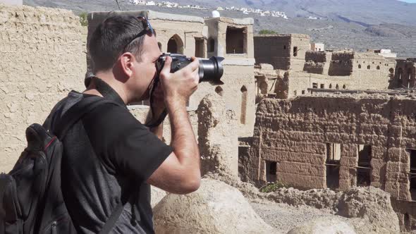 Caucasian Male Tourist Taking Photos of Abandoned Old Ruined Village of Al Hamra Near Nizwa, Oman alt
