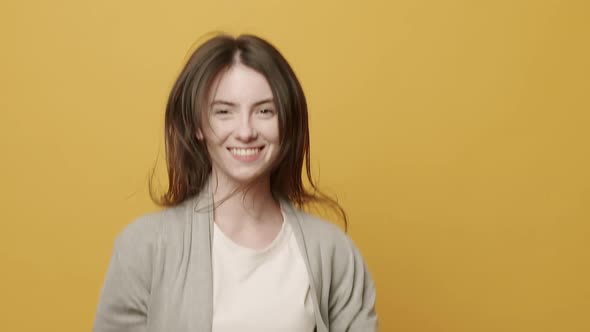 Woman Smiling Dancing to Music Rhythmically to Beat Moving on Yellow Background alt