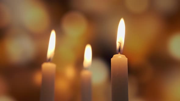 Footage of Burning a Three Candles on on a Yellow Background of Colored Blurred Bokeh alt