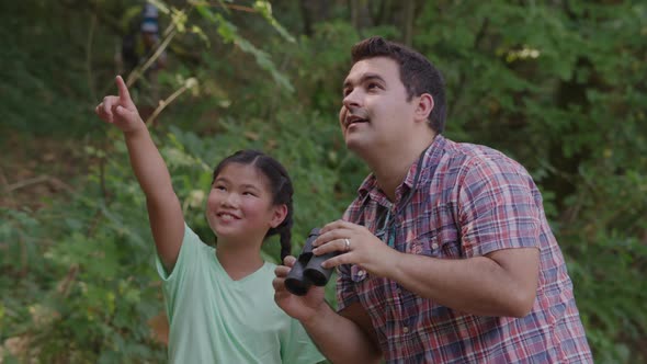 Girl at summer camp looking through binoculars with camp leader