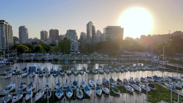 Aerial dolly out of Olivos neighborhood buildings and sailboats parked inline in port at sunset, Bue alt