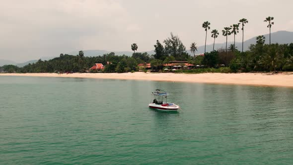 Small motorboat floating on blue turquoise sea water in tropical beach with palms alt