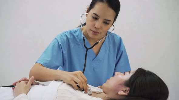 A doctor in hospital use stethoscope check the the lady patient laid on bed. 