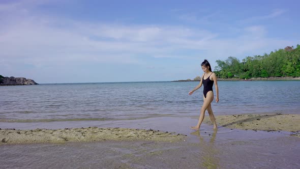 Pretty Asian Woman in Black Swimsuit Walking Alone on a Sandbar Thailand