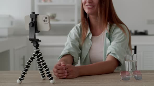 Female Sitting in Front of Smartphone on Tripod Recording Video alt
