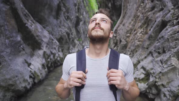 Young man admiring the canyon. There is a creek. alt