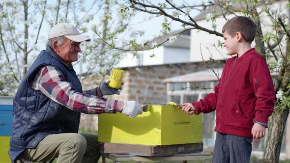 Portrait of Happy Hardworking Beekeepers, an Elderly Smiling Man and His Grandson Rejoice at alt