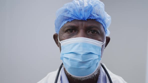 Portrait of african american male doctor wearing face mask and surgical cap alt