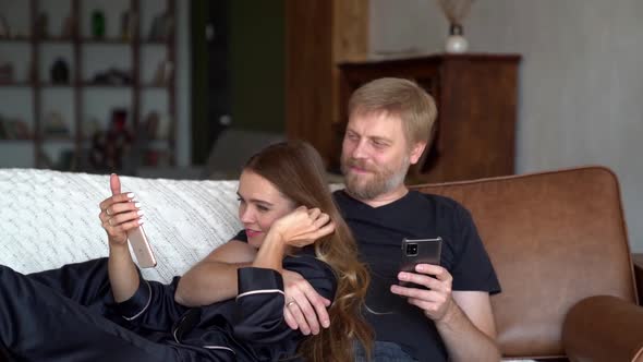 A Man and a Woman in Love Are Hugging and Watching a Funny Video or Picture on the Smartphone alt