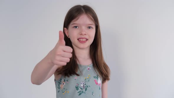 Cute Little Girl Gesturing Thumbs Up and Looking at Camera